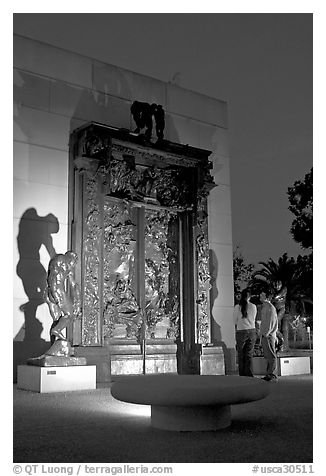 A couple contemplates Rodin's Gates of Hell at night. Stanford University, California, USA (black and white)