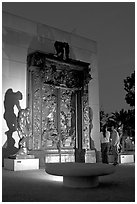 A couple contemplates Rodin's Gates of Hell at night. Stanford University, California, USA (black and white)