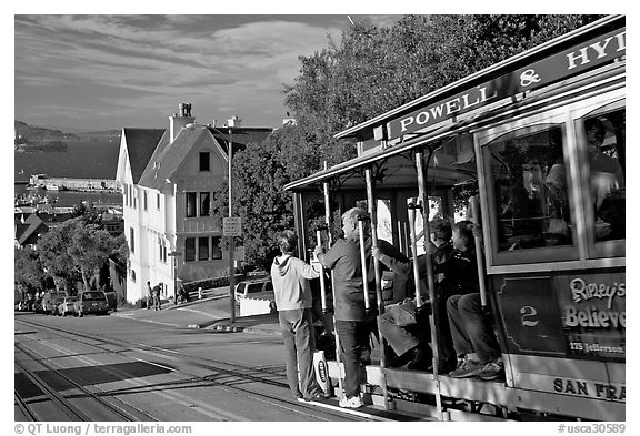 Cable car plunging with people clinging on Hyde Street, late afternoon. San Francisco, California, USA