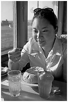 Woman eating a bown of clam chowder on the pier. Santa Cruz, California, USA (black and white)