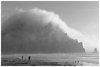 Couple walking on the beach, with Morro Rock and fog behind. Morro Bay, USA (black and white)