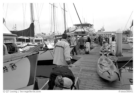 Pier with passengers preparing to board a tour boat with outdoor gear, Ventura. California, USA