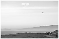 Hang gliders soaring above hikers, Fort Funston, late afternoon. San Francisco, California, USA ( black and white)