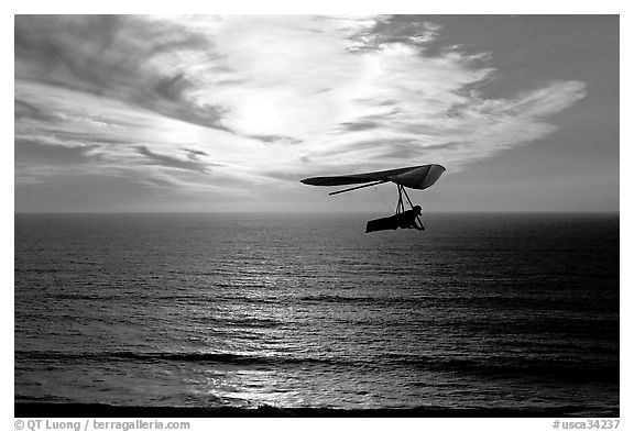 Soaring in a hang glider above the ocean at sunset,  Fort Funston. San Francisco, California, USA (black and white)