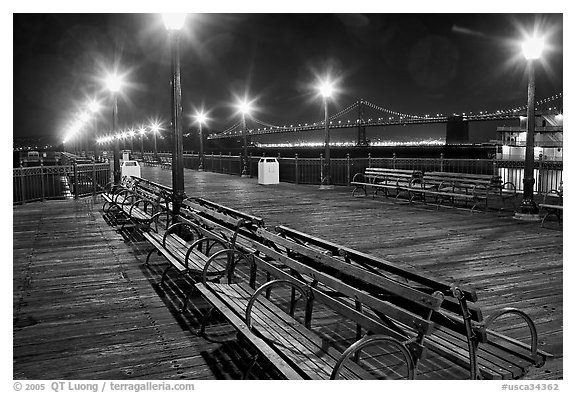 Benches and lights on Pier 7 with Bay Bridge in background, evening. San Francisco, California, USA (black and white)