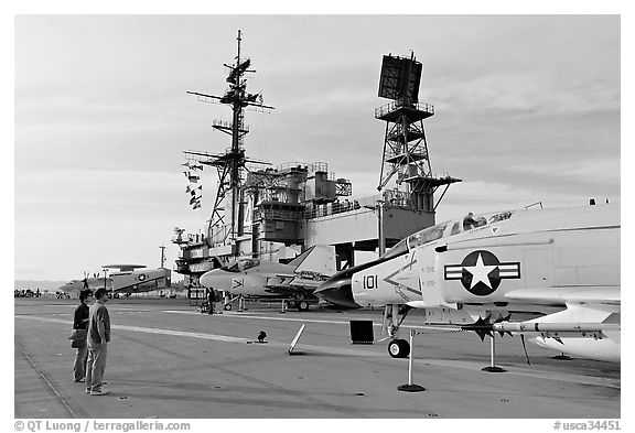 Couple looking at fighter aircraft on the Flight deck of USS Midway. San Diego, California, USA (black and white)