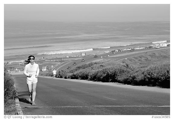 Woman jogging on raod,  Torrey Pines State Preserve. La Jolla, San Diego, California, USA