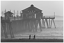 Beachgoers and Huntington Pier, late afternoon. Huntington Beach, Orange County, California, USA (black and white)
