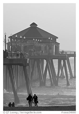 Beachgoers, surfers in waves,  and Huntington Pier. Huntington Beach, Orange County, California, USA (black and white)