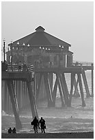 Beachgoers, surfers in waves,  and Huntington Pier. Huntington Beach, Orange County, California, USA ( black and white)