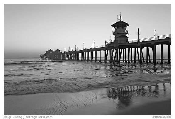 Huntington Pier reflected in wet sand at sunset. Huntington Beach, Orange County, California, USA