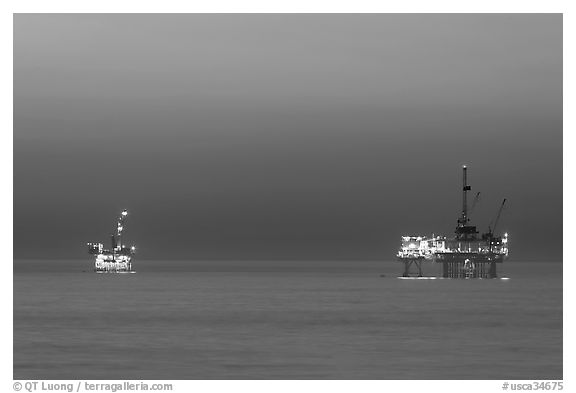 Oil drilling platforms lighted at dusk. Huntington Beach, Orange County, California, USA (black and white)