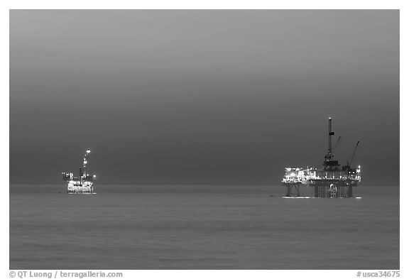 Oil drilling platforms lighted at dusk. Huntington Beach, Orange County, California, USA