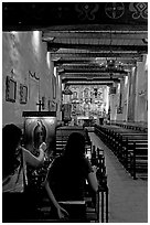 Two women light up candles in the Serra Chapel. San Juan Capistrano, Orange County, California, USA ( black and white)