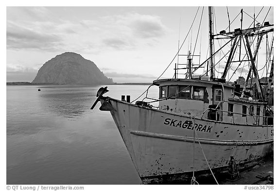 Baat with rusted hull and Morro Rock. Morro Bay, USA (black and white)