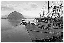 Baat with rusted hull and Morro Rock. Morro Bay, USA (black and white)