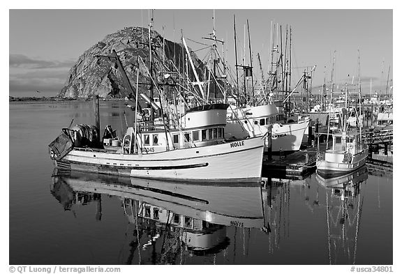 Fishing boats with reflections and Morro Rock, early morning. Morro Bay, USA