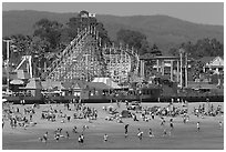 Beachgoers, and Santa Cruz boardwalk roller-coaster. Santa Cruz, California, USA (black and white)