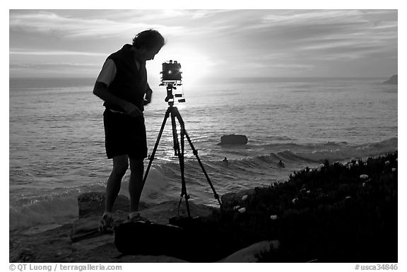 Photographer and large format camera on tripod at sunset. Santa Cruz, California, USA