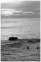 Surfers and rock at sunset. Santa Cruz, California, USA (black and white)