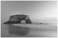 Sea arch and reflection, Natural Bridges State Park, dusk. Santa Cruz, California, USA (black and white)