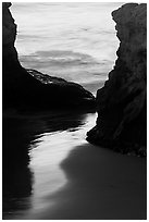 Reflection on wet sand through rock opening, Natural Bridges State Park, dusk. Santa Cruz, California, USA (black and white)
