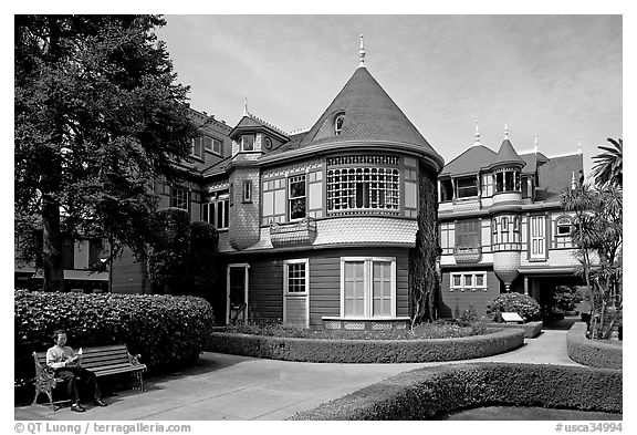 Woman reading on a bench in the gardens. Winchester Mystery House, San Jose, California, USA (black and white)