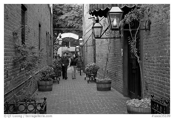 Couple walking in an alley of brick walls, San Pedro Square. San Jose, California, USA (black and white)