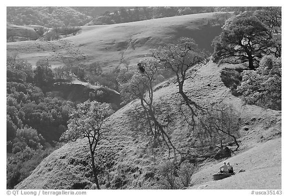 Couple sitting on hillside in early spring, Sunol Regional Park. California, USA (black and white)