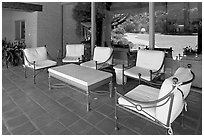 Chairs and coffee table on porch, Sunset gardens reflected. Menlo Park,  California, USA (black and white)