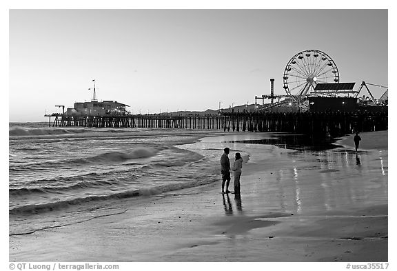 Couple on beach, with pier in the background, sunset. Santa Monica, Los Angeles, California, USA (black and white)