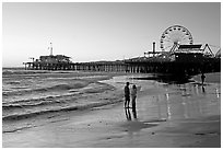 Couple on beach, with pier in the background, sunset. Santa Monica, Los Angeles, California, USA (black and white)