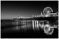 Ferris Wheel and pier reflected on wet sand at night. Santa Monica, Los Angeles, California, USA ( black and white)