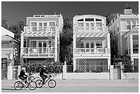 Family cycling in front of colorful beach houses. Santa Monica, Los Angeles, California, USA (black and white)