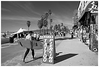 Surfer walking on Ocean Front Walk. Venice, Los Angeles, California, USA ( black and white)