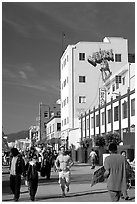 Jogger in the crowd of Ocean Front Walk, with a Venice Mural behind. Venice, Los Angeles, California, USA (black and white)