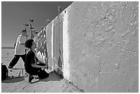 Young men creating graffiti art on a wall on the beach. Venice, Los Angeles, California, USA (black and white)