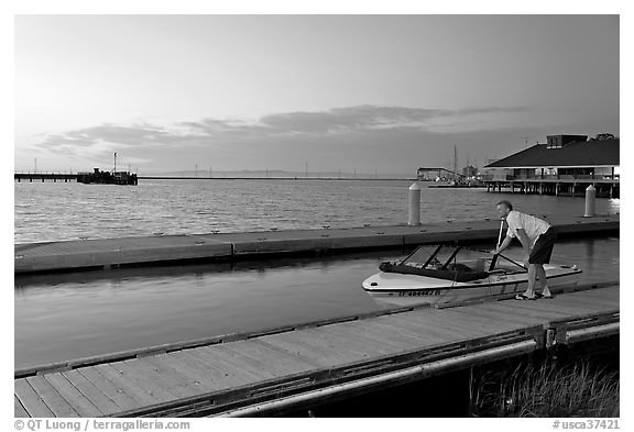 Man holding small boat, Redwood marina, sunset. Redwood City,  California, USA