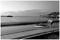 Man holding small boat, Redwood marina, sunset. Redwood City,  California, USA (black and white)