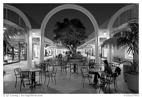 Sitting at outdoor table at night, Stanford Shopping Center. Stanford University, California, USA (black and white)