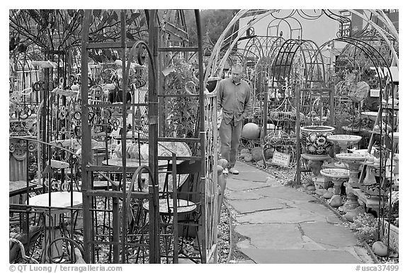 Man browsing in colorful outdoor antique display. Half Moon Bay, California, USA (black and white)