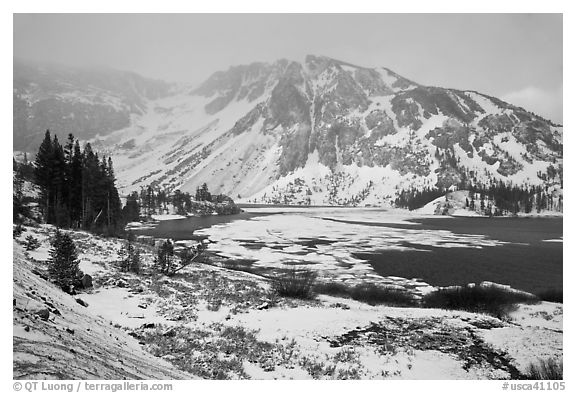 Partly frozen Ellery Lake and mountains with snow. California, USA