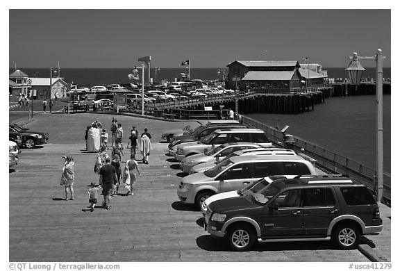 People drapped with colorful towels walking on wharf. Santa Barbara, California, USA (black and white)