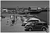 People drapped with colorful towels walking on wharf. Santa Barbara, California, USA (black and white)