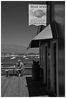 Man eating on wharf next to Fish and Chips restaurant. Santa Barbara, California, USA ( black and white)