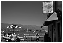 People eating with yachts and beach in background. Santa Barbara, California, USA (black and white)