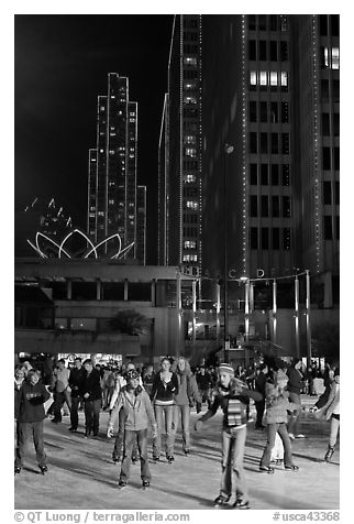 People skating on ice ring at night, Embarcadero Center. San Francisco, California, USA (black and white)