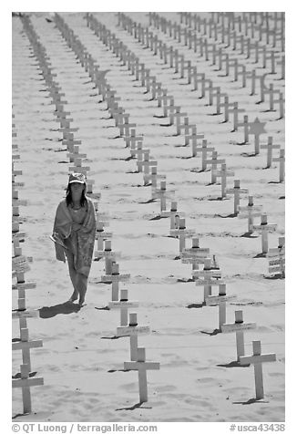 Girl wrapped in towel walking amongst crosses on beach. Santa Monica, Los Angeles, California, USA (black and white)