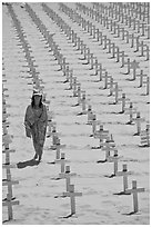 Girl wrapped in towel walking amongst crosses on beach. Santa Monica, Los Angeles, California, USA (black and white)