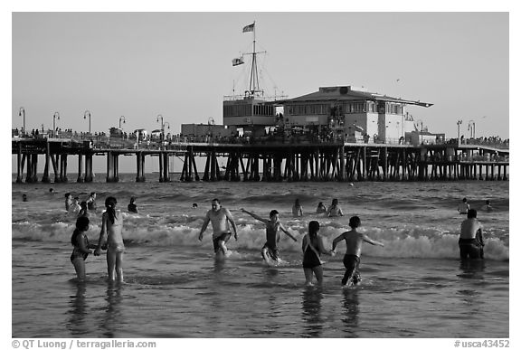 People bathing in ocean and Santa Monica Pier, late afternoon. Santa Monica, Los Angeles, California, USA (black and white)